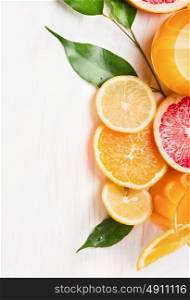 Citrus juice and sliced fruits: orange, lemon and grapefruit on white wooden background