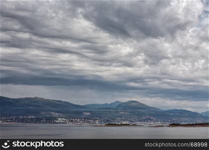 City and mountains along the Romsdalsfjorden near Andalsnes under a cloudy sky, Norway. Along the Romsdalsfjorden near Andalsnes, Norway