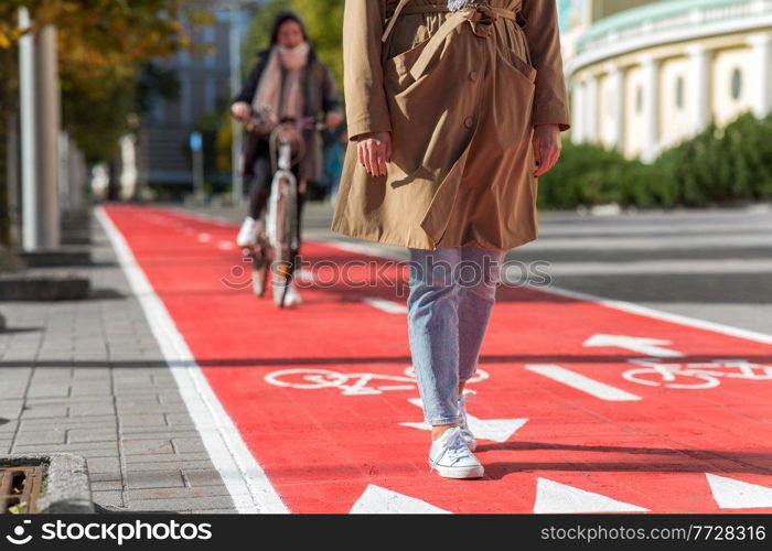 city and traffic concept - close up of woman walking along separate bike lane or red road with signs only for bicycles on street. woman walking along bike lane or road for bicycles