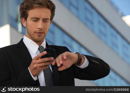 City businessman checking his watch and his phone