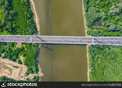 City car moving at highway bridge on background smooth river surface drone view. Aerial view