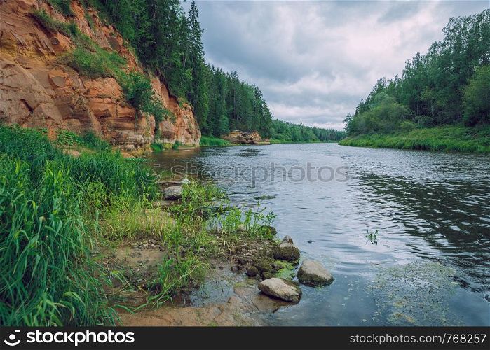 City Cesis, Latvia Republic. Red rocks and river Gauja. Nature and green trees in summer. Jul 5. 2019 Travel photo.