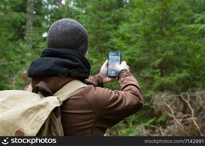 City Cesis, Latvia republic. The photographer is still photographing the forest landscape with phone. 2. november.