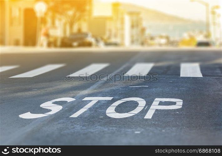 City crosswalk with symbol stop, closeup road texture with blurred San Francisco Bay in background in a warm sunny day