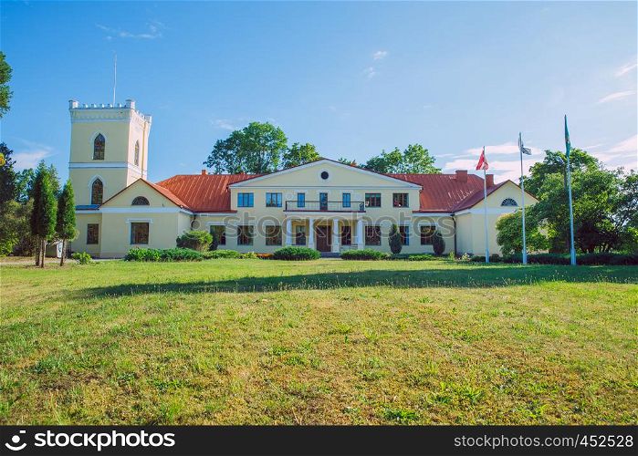 City Dzerbene, Latvia. Old manor house and meadow, green trees. Travel photo 2018.