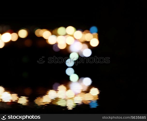 City lights in the background with blurring spots of light reflected in water below