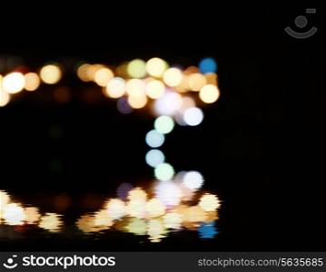 City lights in the background with blurring spots of light reflected in water below