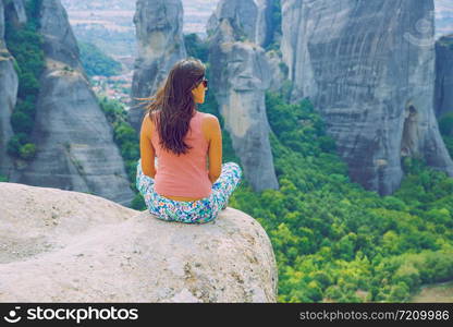 City Meteora, Greek Republic. Big mountains and girl sit on rock. 12. Sep. 2019. Travel photo.