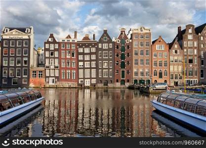 City of Amsterdam at sunset in Netherlands, terraced Dutch style historic houses with reflections on water.