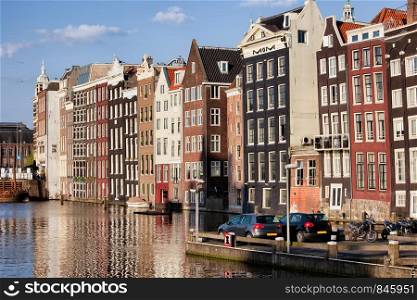 City of Amsterdam at sunset, picturesque historical row houses by the canal, North Holland, Netherlands.