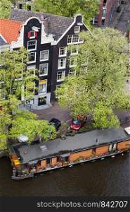 City of Amsterdam traditional Dutch style houses and a houseboat on a canal in Netherlands, view from above.