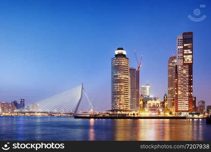 City of Rotterdam downtown skyline at dusk in South Holland, Netherlands, Erasmus Bridge on the left.