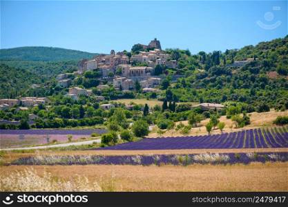 City of Saint-Saturnin-les-Apt on the hill with lavender fields in valley on summer day. Provence, France