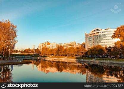 City ponds in the autumn. Trees covered with yellow and orange leaves are reflected in the water. Blue sky.. Khabarovsk, Russia - Sep 27, 2018  Urban ponds in the fall