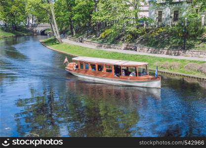 City Riga, Latvia Republic. Tourists on a boat ride through the city canal. Around the trees and nature. May 7. 2019 Travel photo.