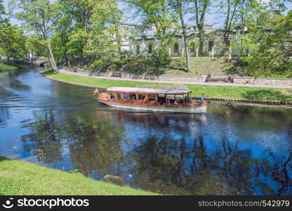 City Riga, Latvia Republic. Tourists on a boat ride through the city canal. Around the trees and nature. May 7. 2019 Travel photo.