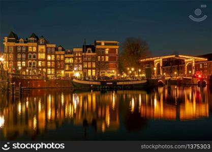 City scenic from Amsterdam at the river Amstel in the Netherlands at night