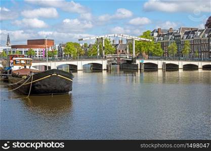 City scenic from Amsterdam at the river Amstel in the Netherlands with the Tiny Bridge