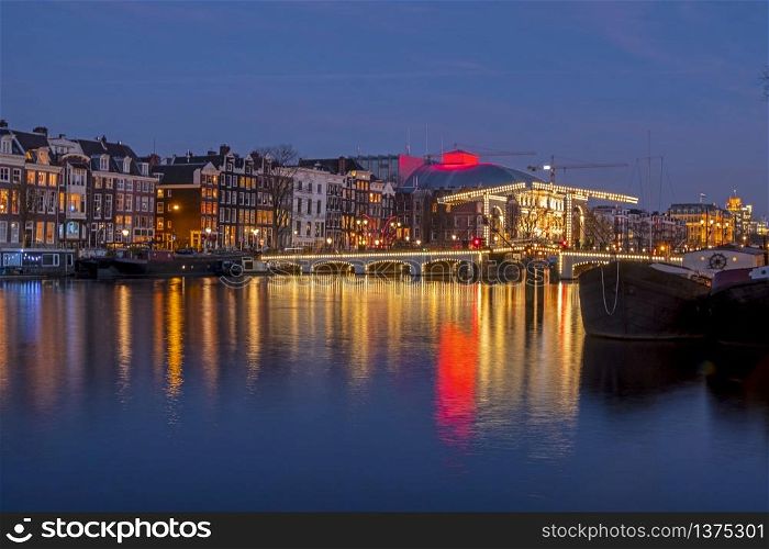 City scenic from Amsterdam at the river Amstel with the Tiny bridge in the Netherlands at night