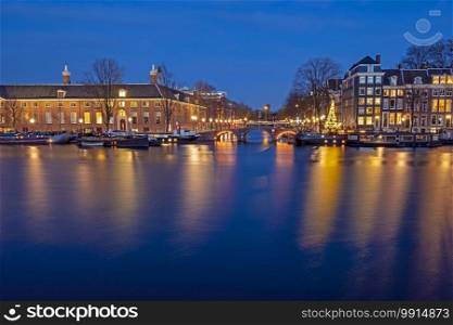 City scenic from Amsterdam by night at the river Amstel in the Netherlands