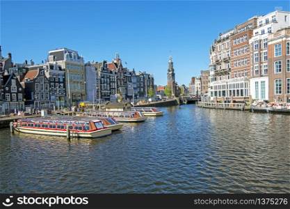 City scenic from Amsterdam with the Munt tower in the Netherlands at the river Amstel
