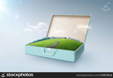 City skyline, green field, mountain and curvy asphalt highway in an open retro vintage suitcase isolated on light blue background .