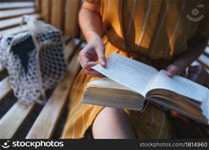 city Style. a girl sits on a bench and reads a book