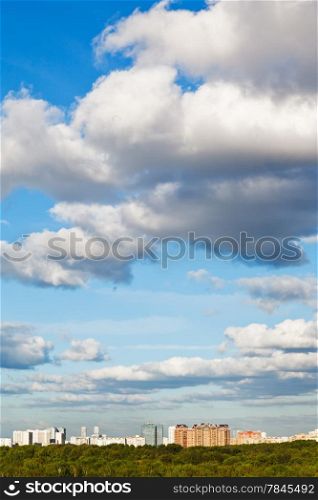 city under big white clouds in spring blue sky