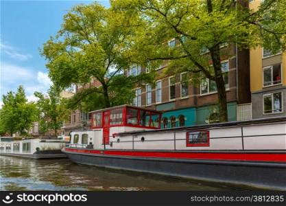 City view of Amsterdam canal and typical houseboat, Holland, Netherlands.