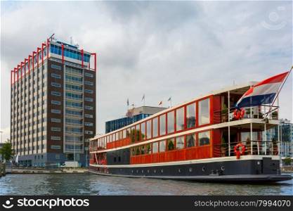 City view of Amsterdam canal, boat and modern building, Holland, Netherlands.