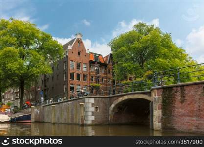 City view of Amsterdam canal, bridge and typical houses, boats and bicycles, Holland, Netherlands.