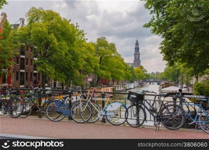 City view of Amsterdam canal, church Westerkerk and typical houses, boats and bicycles, Holland, Netherlands.