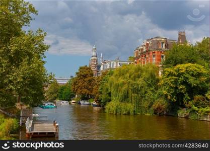 City view of Amsterdam canal, jetty and boats, Holland, Netherlands.