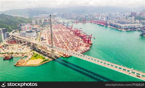 Cityscape drone aerial view of Hong Kong city, port industrial district, cargo container ship, cranes, car traffic on Stonecutters bridge. Logistic industry or freight transportation business concept