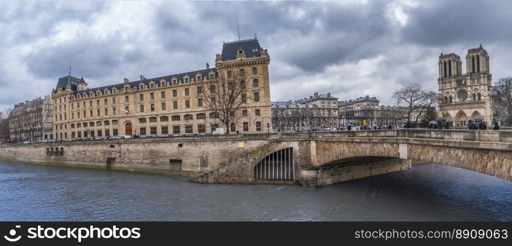 Cityscape in Paris with the Seine river, historical cathedral  and buildings, an antique bridge, on a rainy day of February.