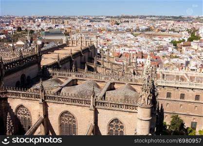 Cityscape of Seville in Spain, on the first plan Gothic style rooftop of Seville Cathedral, El Arenal historic quarter and Triana district at the far end.