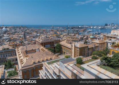 Cityscape of the Genoa city, Italy, with its colorful and crowded buildings and the famous big seaport, on a sunny day of summer.