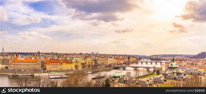 Cityscape panorama of Prague, the capital of Czech Republic, with the Vltava river, the bridges, and all its buildings, under an afternoon sky.