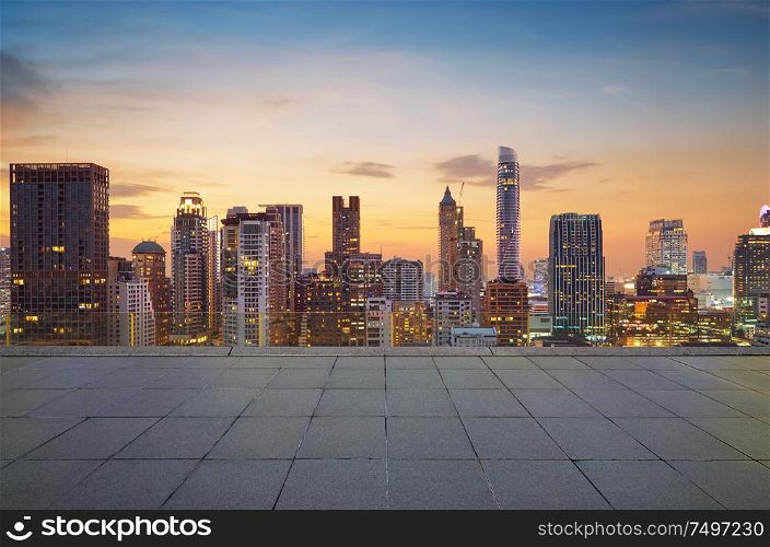 Cityscape sunset view of Bangkok modern office business building and high skyscraper in business district with marble floor in front .