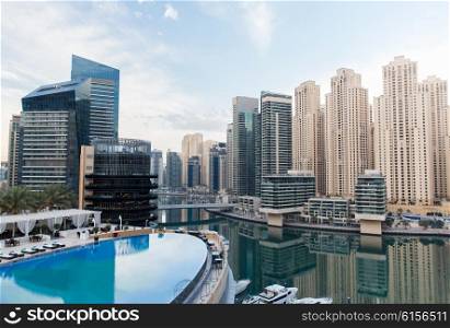 cityscape, travel, tourism and urban concept - Dubai city district skyscrapers and seafront with hotel infinity edge pool