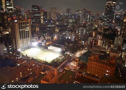 Cityscape view with skyscrapers and sports field at night, Tokyo, Japan