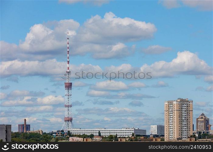 Cityscape with a TV tower and a TV center in Kyiv against a blue cloudy sky on a summer day. Copy space.. Television tower and television center in Kyiv against a blue cloudy sky.