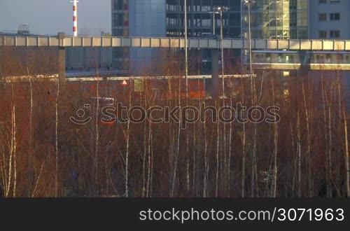 Cityscape with passing SkyTrain and bare trees in Dusseldorf, Germany. Modern public transport carrying passengers from the station to airport terminal