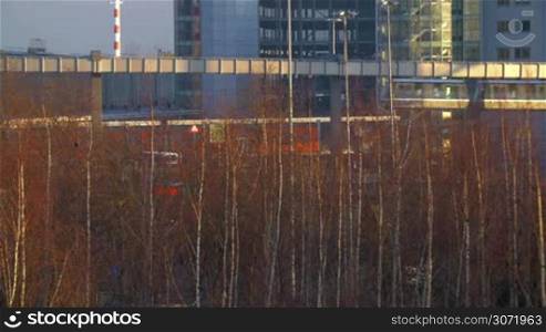 Cityscape with passing SkyTrain and bare trees in Dusseldorf, Germany. Modern public transport carrying passengers from the station to airport terminal
