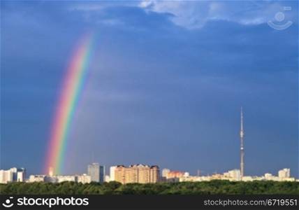 cityscape with rainbow under city in blue sky