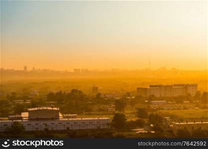 Cityscape with sunset in big city, industrial buildings under dramatic sunset sky