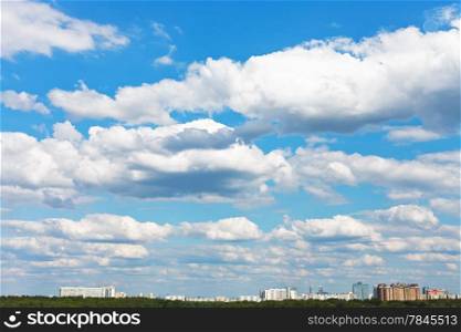 cityscape with white fluffy clouds in spring blue sky
