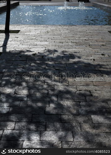 Cityspace. Stone road, pavement in city park or garden and fountain in the background