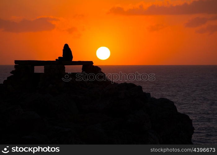 Ciutadella Menorca at Punta Nati orange sunset with girl backlight