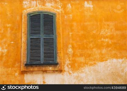 Ciutadella Menorca wooden shutter window on grunge yellow downtown wall at Balearic islands
